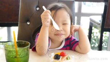 女孩用勺子吃甜的水果挞